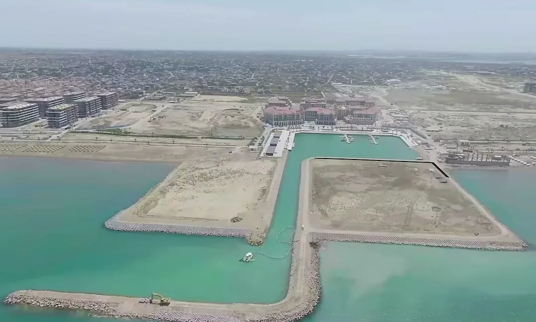 Гавань с моря, май 2026: Marina Village в центре, участок Marina Bay — левее, ровная земля без корпусов